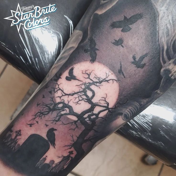 a man's arm with a tree and birds on it