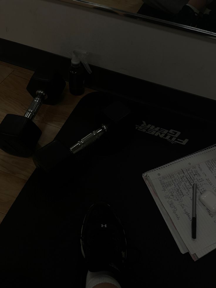 a person writing on a piece of paper next to a pair of black dumbbells