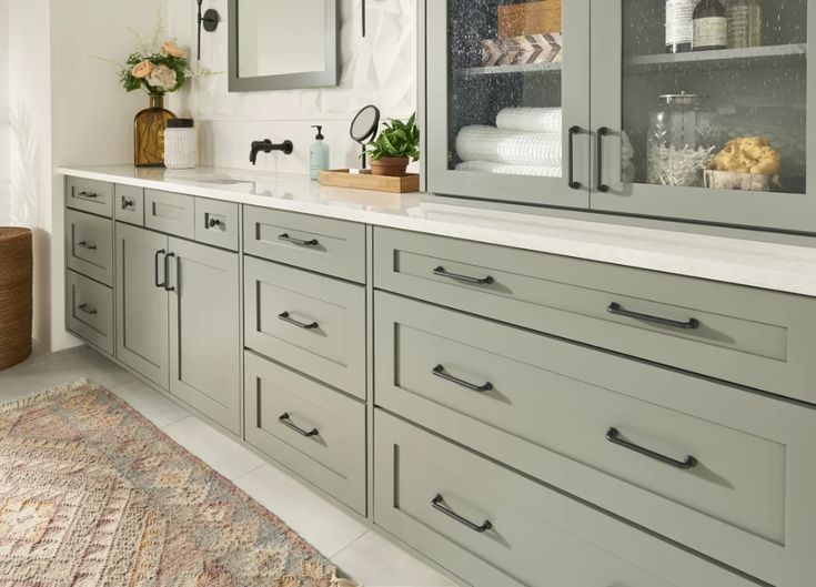 a large bathroom with gray cabinets and white counter tops, along with a rug on the floor