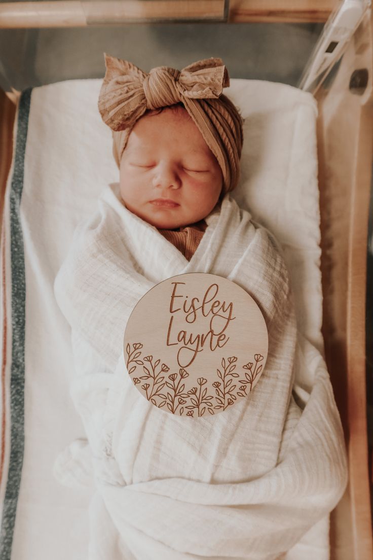 a newborn baby wrapped in a blanket with a name tag on it's side