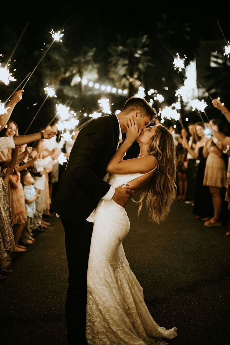 a newly married couple kissing while surrounded by sparklers