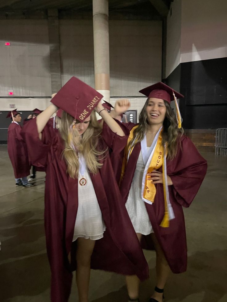 two girls in graduation gowns and caps are posing for the camera with their arms around each other