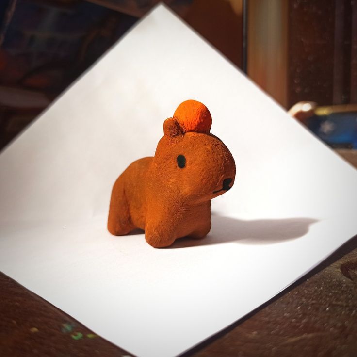 Capybara with orange on its head Cute Clay Capybara, Gort Capybara, Cute Mini Sculptures, Capybara Clay Sculpture, Easy Sculpey Clay Ideas, Air Dry Clay Capybara, Simple Clay Figures, Polymer Clay Capybara, Capybara Clay Art