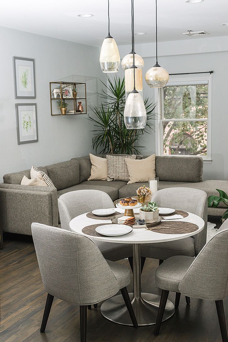 a living room filled with furniture and a dining table in front of a large window