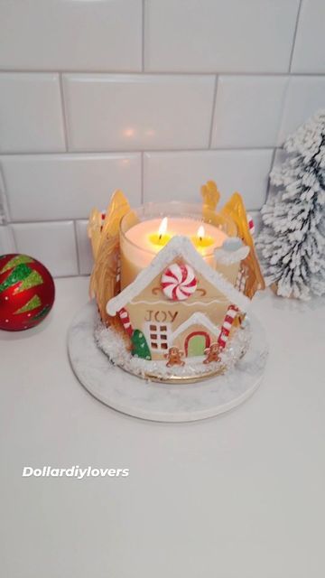 a lighted gingerbread house sits on a counter next to christmas decorations