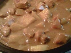 a close up of a bowl of soup with meat and vegetables in it on a table