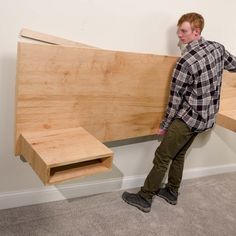 a man standing next to a large wooden object in a room with carpeted flooring