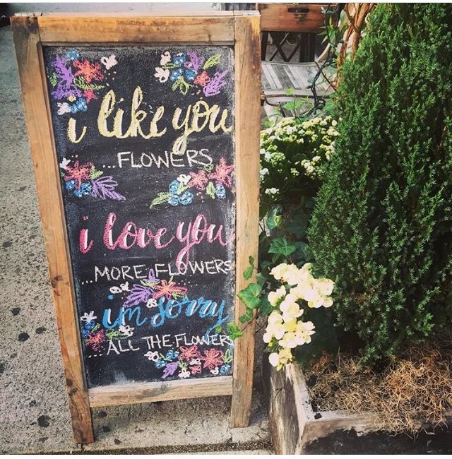 a chalkboard sign with flowers on it