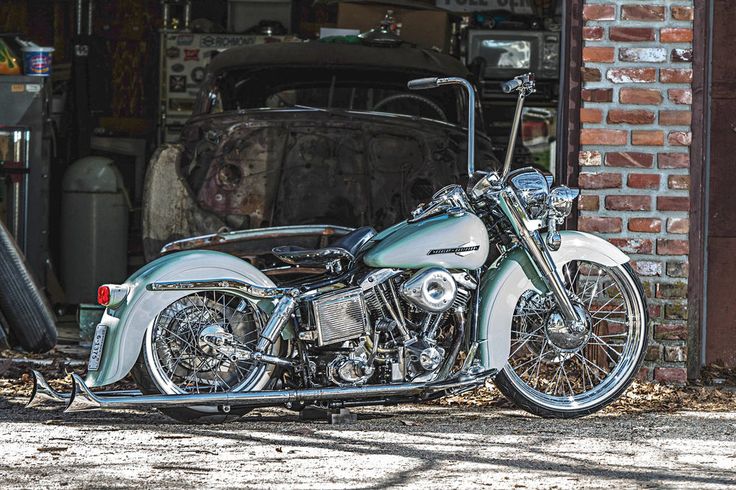 a silver motorcycle parked in front of a brick building with an open garage door behind it