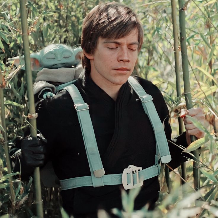 a man with a baby yoda doll on his back in the middle of tall grass