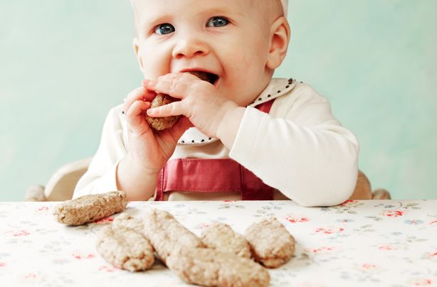 a baby sitting at a table eating cookies