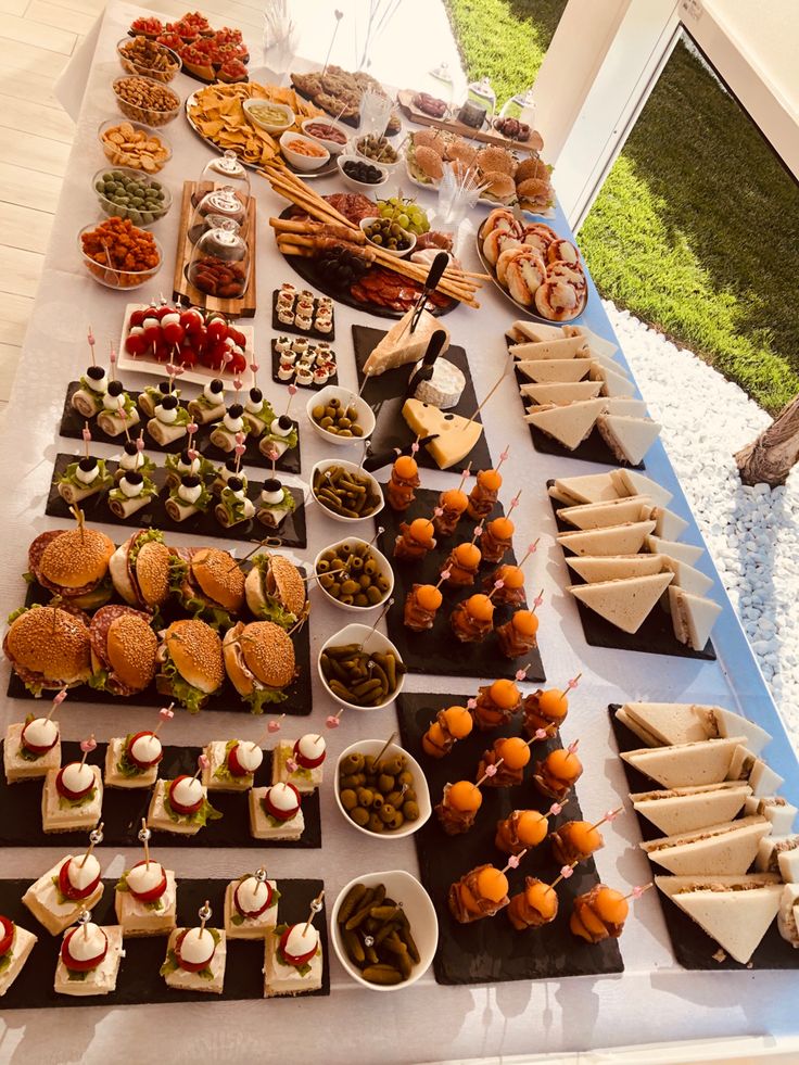 a table filled with lots of different types of food on plates and trays next to each other