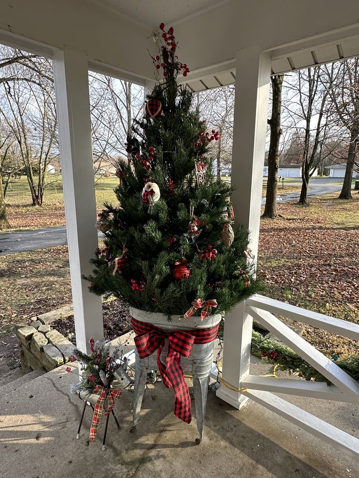 a potted christmas tree sitting on top of a porch