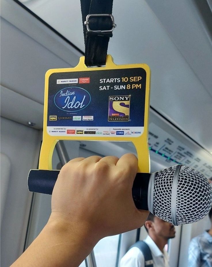 a person holding a microphone up to a sign that says start to see someone on the bus