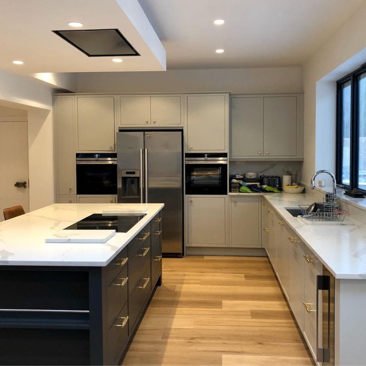 a large kitchen with stainless steel appliances and white counter tops, along with hardwood flooring