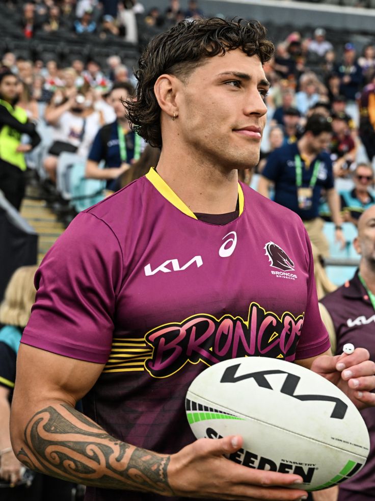 a man holding a rugby ball in front of a crowd