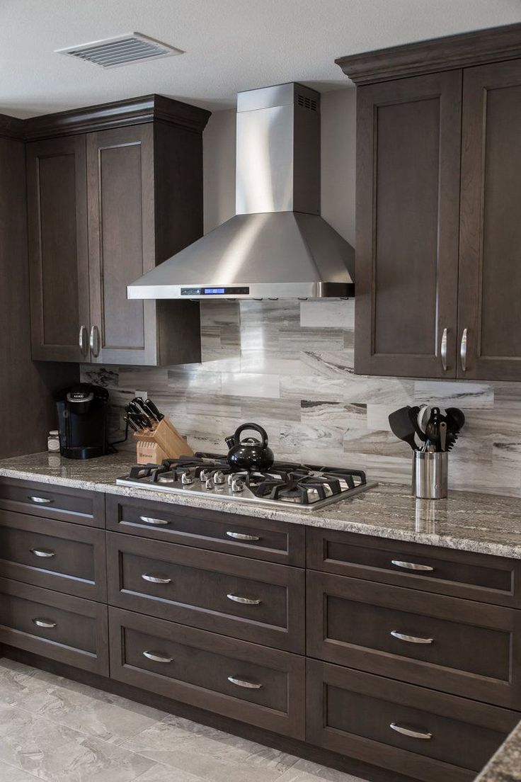 a kitchen with marble counter tops and dark wood cabinets