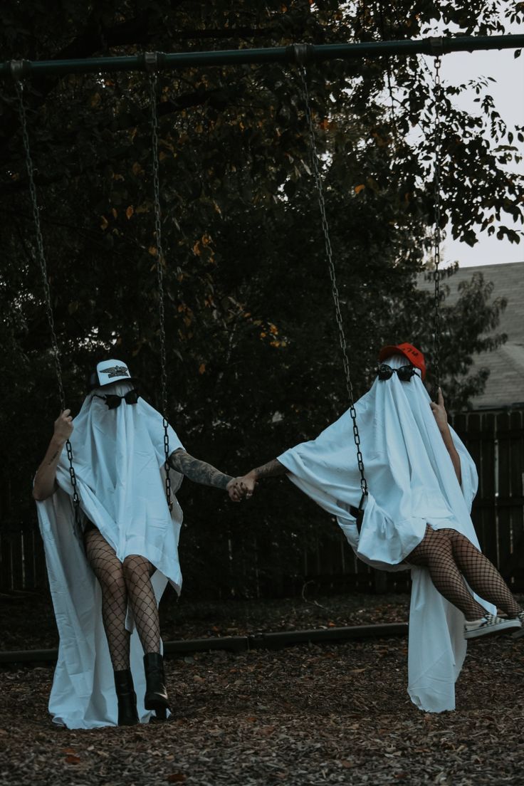 two people in white robes holding hands on a swing