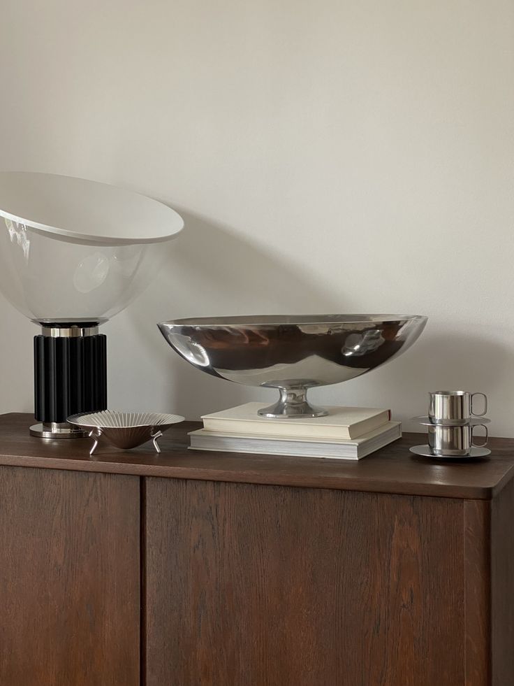 a table with a bowl, book and other items on it in front of a white wall