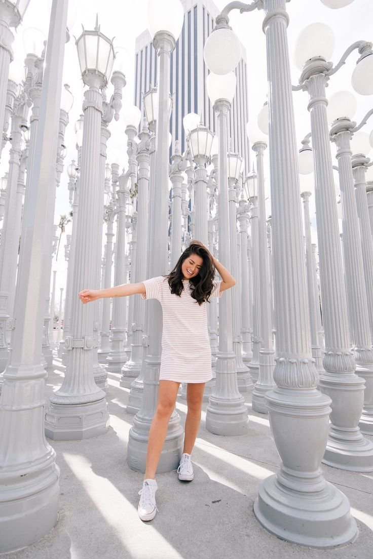 a woman posing for a photo in front of many white lamps and street lights with her arms outstretched