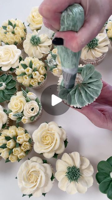 someone is decorating cupcakes with white flowers