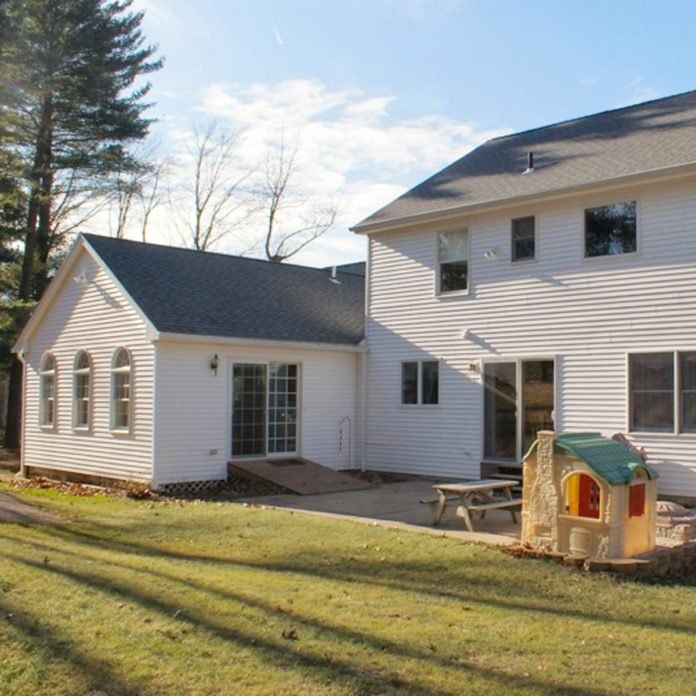 a white house with a small birdhouse in the front yard and picnic table on the lawn