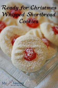 some cookies are sitting in a glass dish with powdered sugar on top and the words ready for christmas whipped shortbread cookies