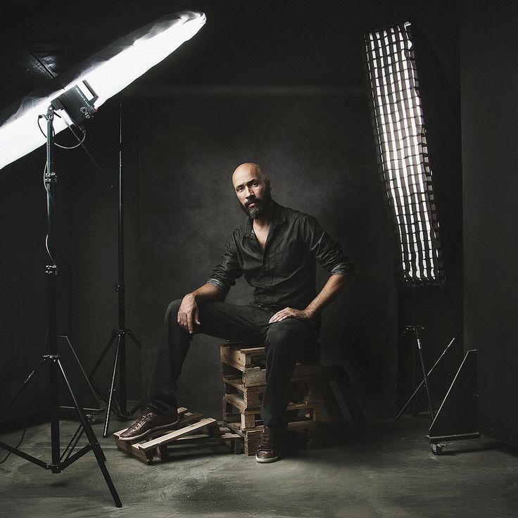 a man sitting on top of a wooden box in front of a camera and light