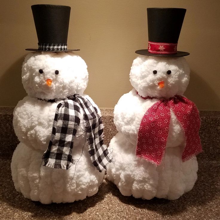 two snowmen with hats and scarfs on their heads