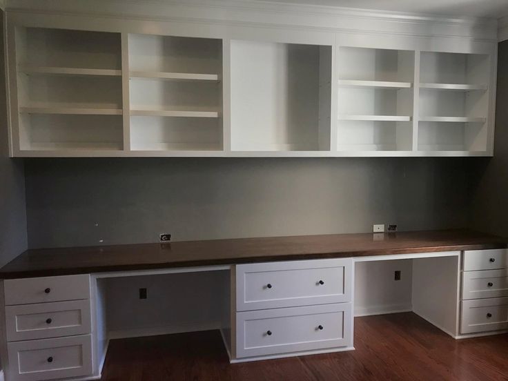 an empty room with white cabinets and wood floors