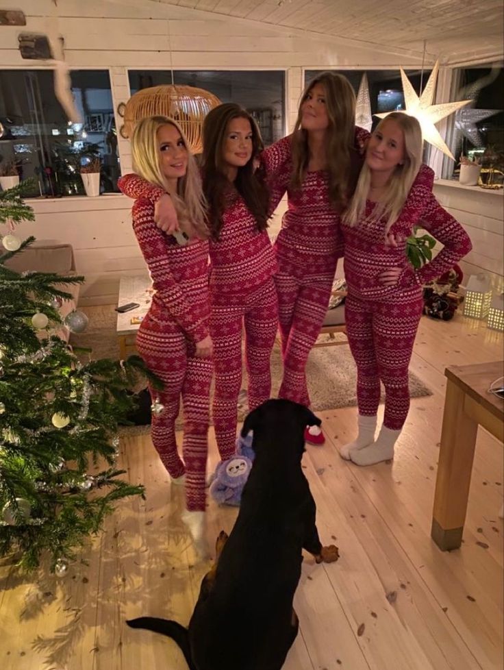 three women in matching pajamas standing next to a dog