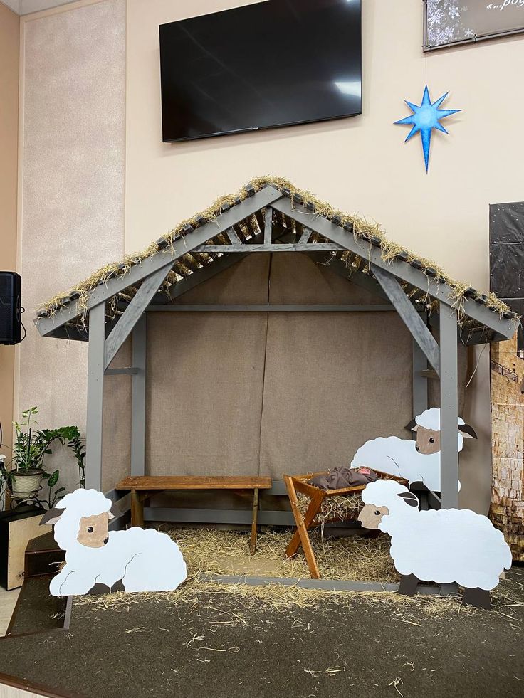 a nativity scene with sheep and a manger stable in the middle of it