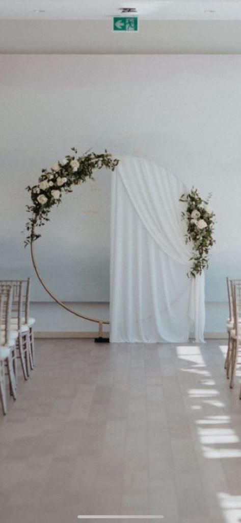 an empty room with white chairs and flowers