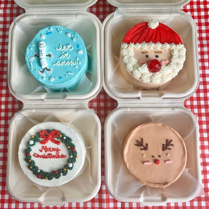 four different decorated cakes in plastic containers on a red and white checkered tablecloth