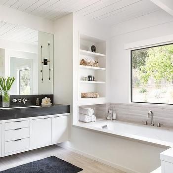 a large bathroom with white cabinets and black counter tops, along with a bathtub