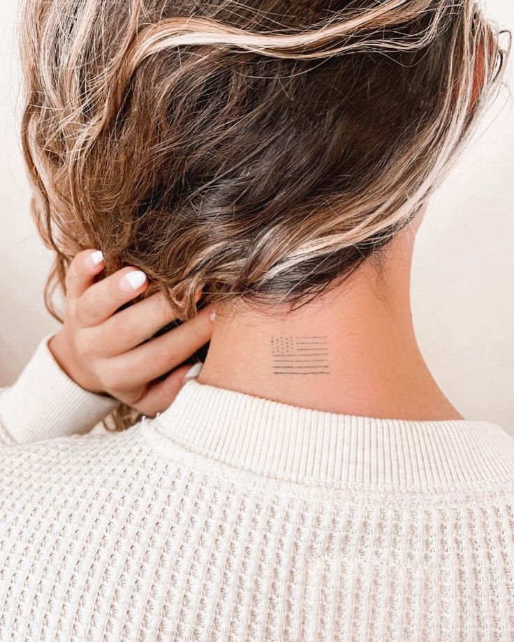 the back of a woman's head with a tattoo on her left side neck