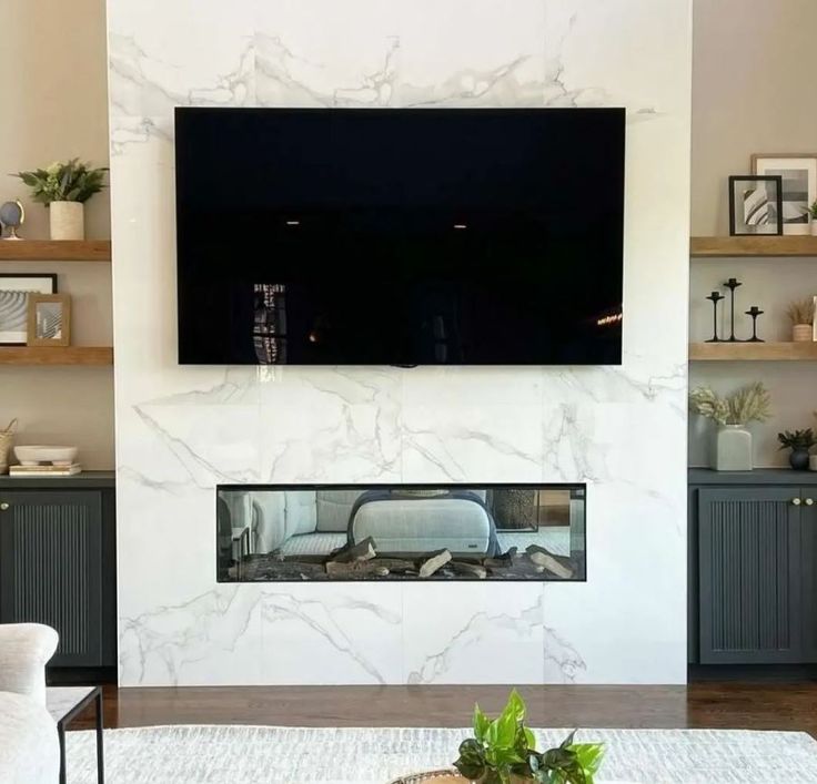 a large flat screen tv mounted on the wall above a fireplace in a living room