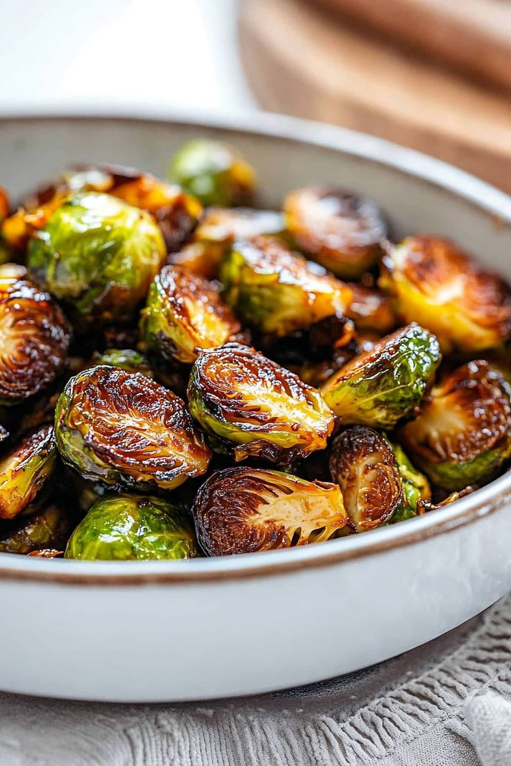 brussel sprouts in a white bowl on top of a tablecloth