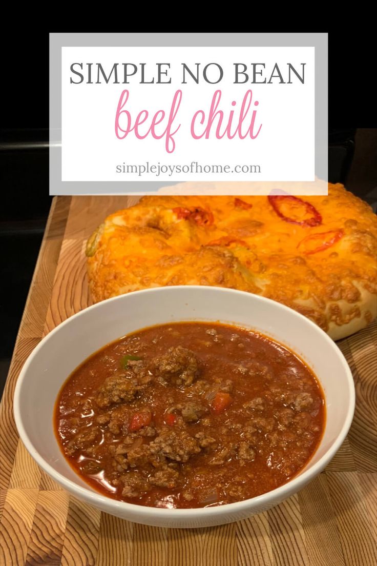 a bowl of beef chili next to a loaf of bread