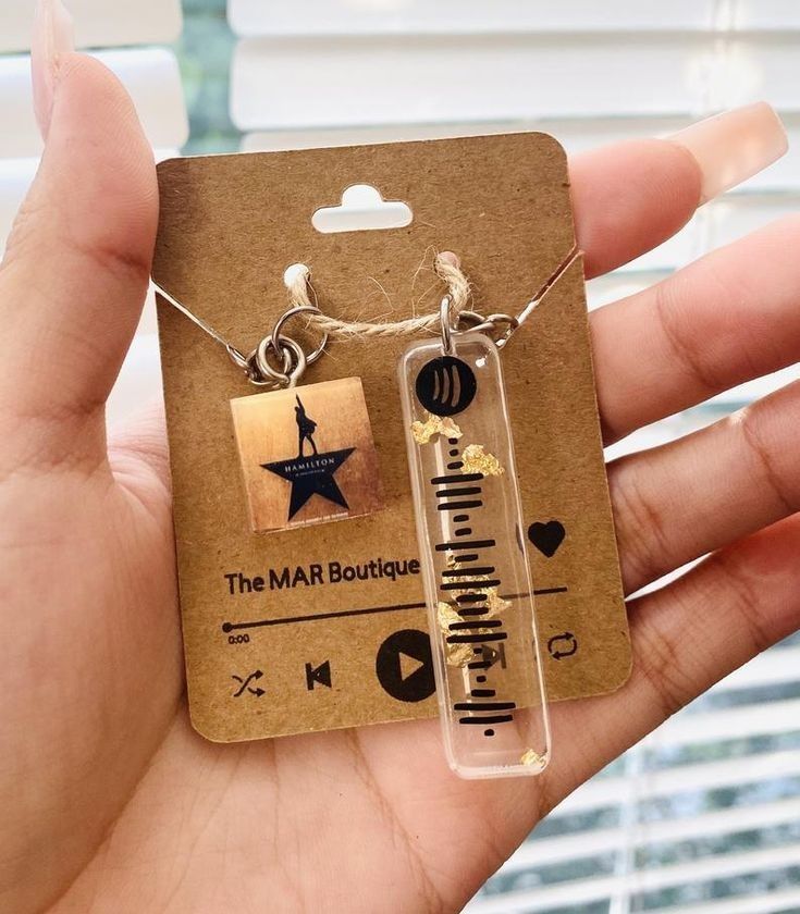 a person holding up a necklace with the words, the mar boutique and an arrow on it