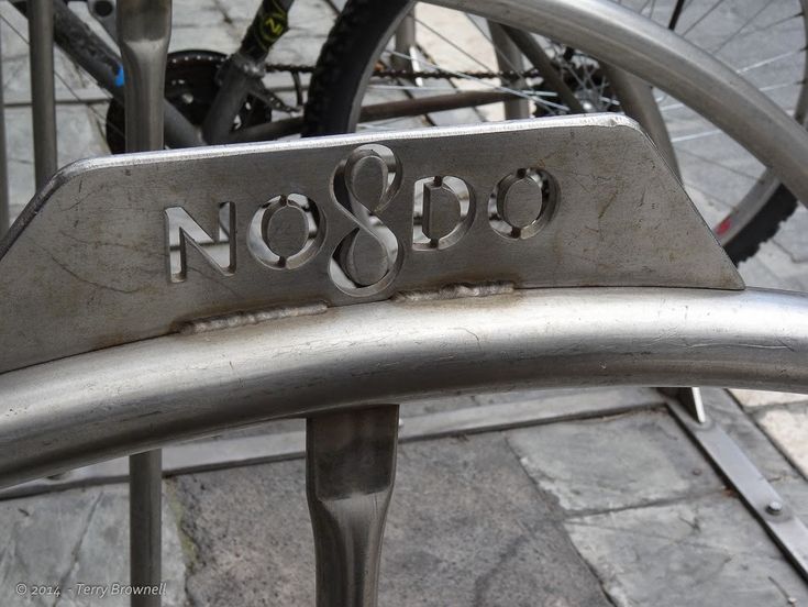 the word no and o is engraved on an iron bench with bicycles in the background