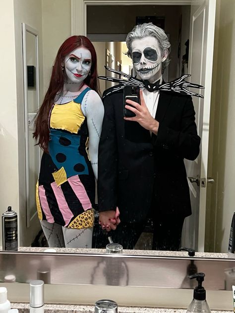 two people dressed up in halloween costumes standing in front of a bathroom mirror with makeup on