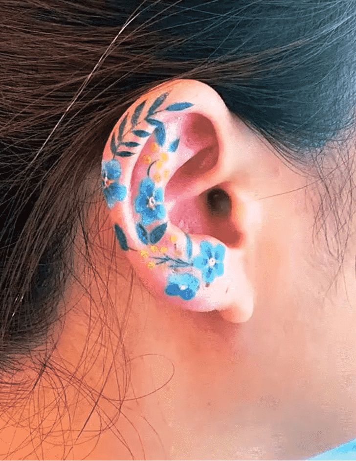 a woman with blue flowers painted on her ear and behind the ear is an ear piercing