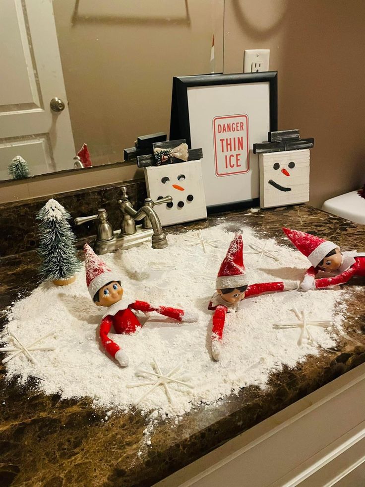 three elfs in the snow on top of a counter