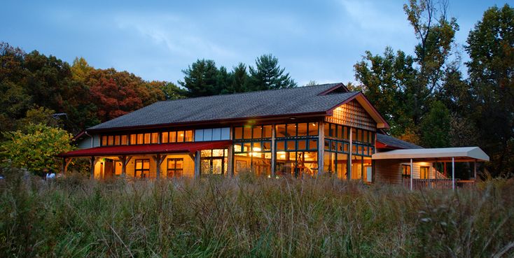 a large house sitting on top of a lush green field next to tall grass and trees