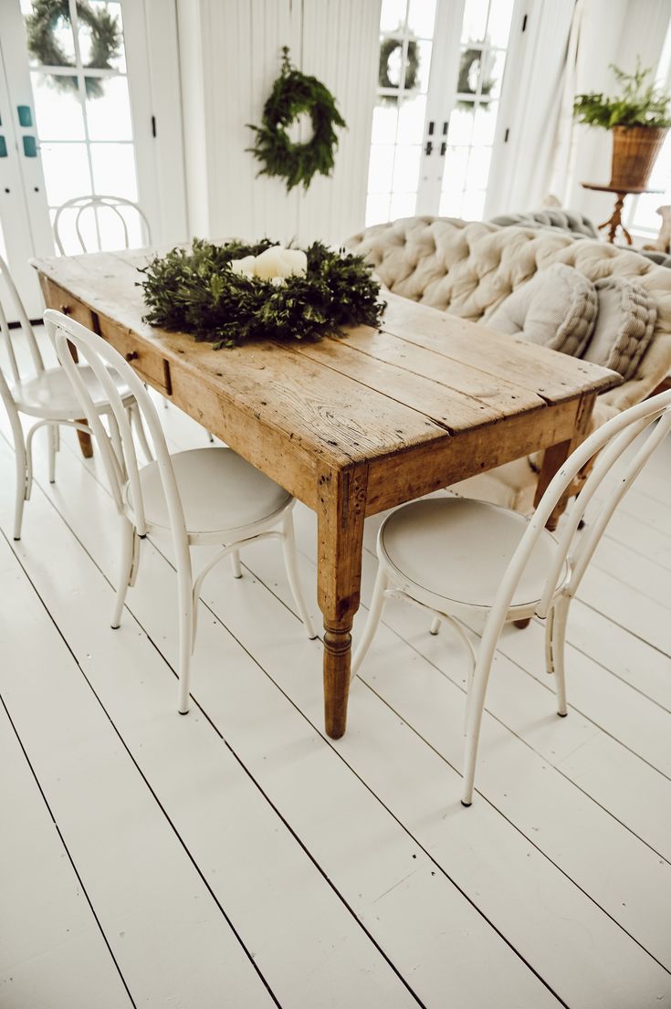 a wooden table sitting on top of a white floor next to chairs and a couch