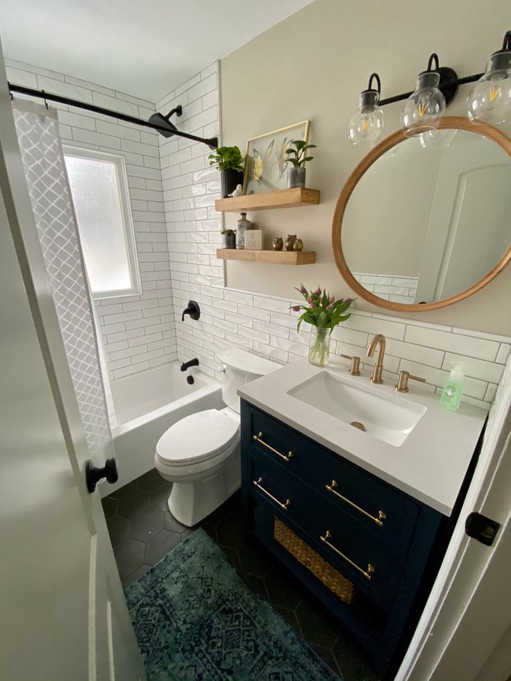 a white toilet sitting next to a sink in a bathroom under a large round mirror