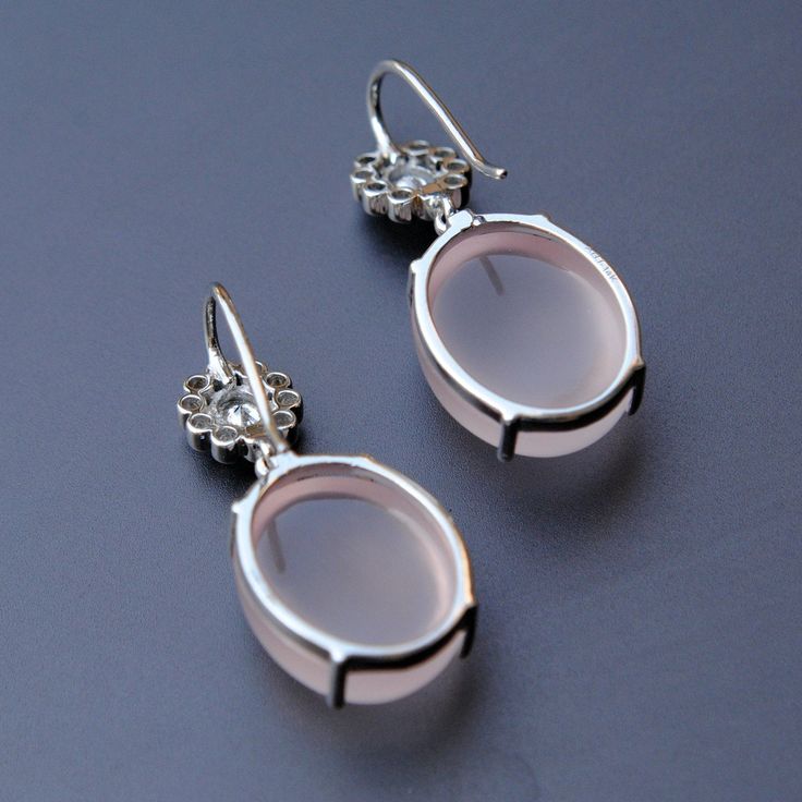 "Subtle oval shaped cabochon rose quartz, dangling from an oval diamond flower, set in 14k white gold, these stunners make for those perfect and unique wedding earrings. An exclusive piece from our shop, these earrings are absolutely to die for..! Oval Diamond - Dangle Earrings - 14K Gold - Rose Quartz - Wedding Earrings - Gemstone Bridal Earrings * Gemstone 1 : Natural Diamonds. * Diamond Wt. : 0.37 Cts (Oval Cut) + 0.25 cts (Round) * Color-Clarity Grade : G Color, Vs Purity * Gemstone 2 : Natu Elegant Sterling Silver Oval Cabochon Earrings, Elegant Oval Cabochon Sterling Silver Earrings, Elegant Silver Oval Cabochon Earrings, Elegant Oval Earrings With Rose Cut Diamonds, Elegant Oval Rose Cut Diamond Earrings, Pink Oval Hallmarked Earrings, Unique Wedding Earrings, Rose Quartz Wedding, Pin It Button