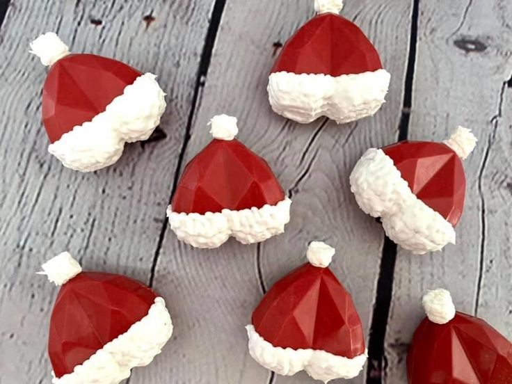 some red and white santa hats are sitting on a wooden table next to each other