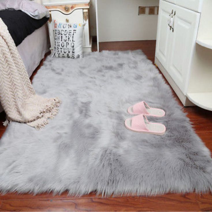 a pair of pink slippers sitting on top of a fluffy gray rug in a bedroom